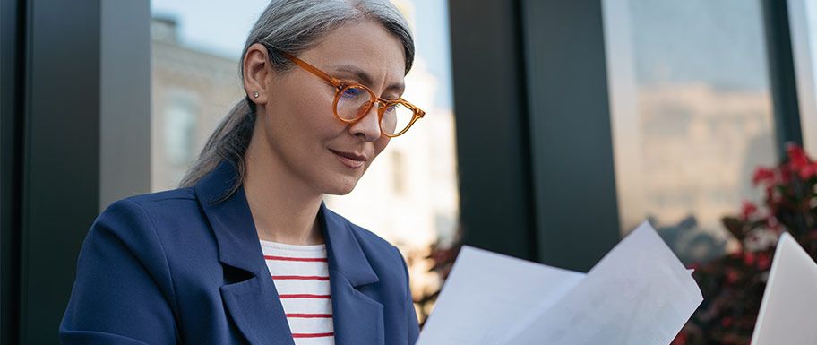 Middle aged woman looking thoughtfully at papers.